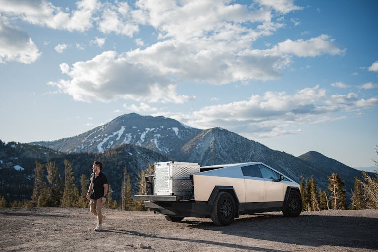 A modern vehicle in a mountainous landscape under a blue sky.