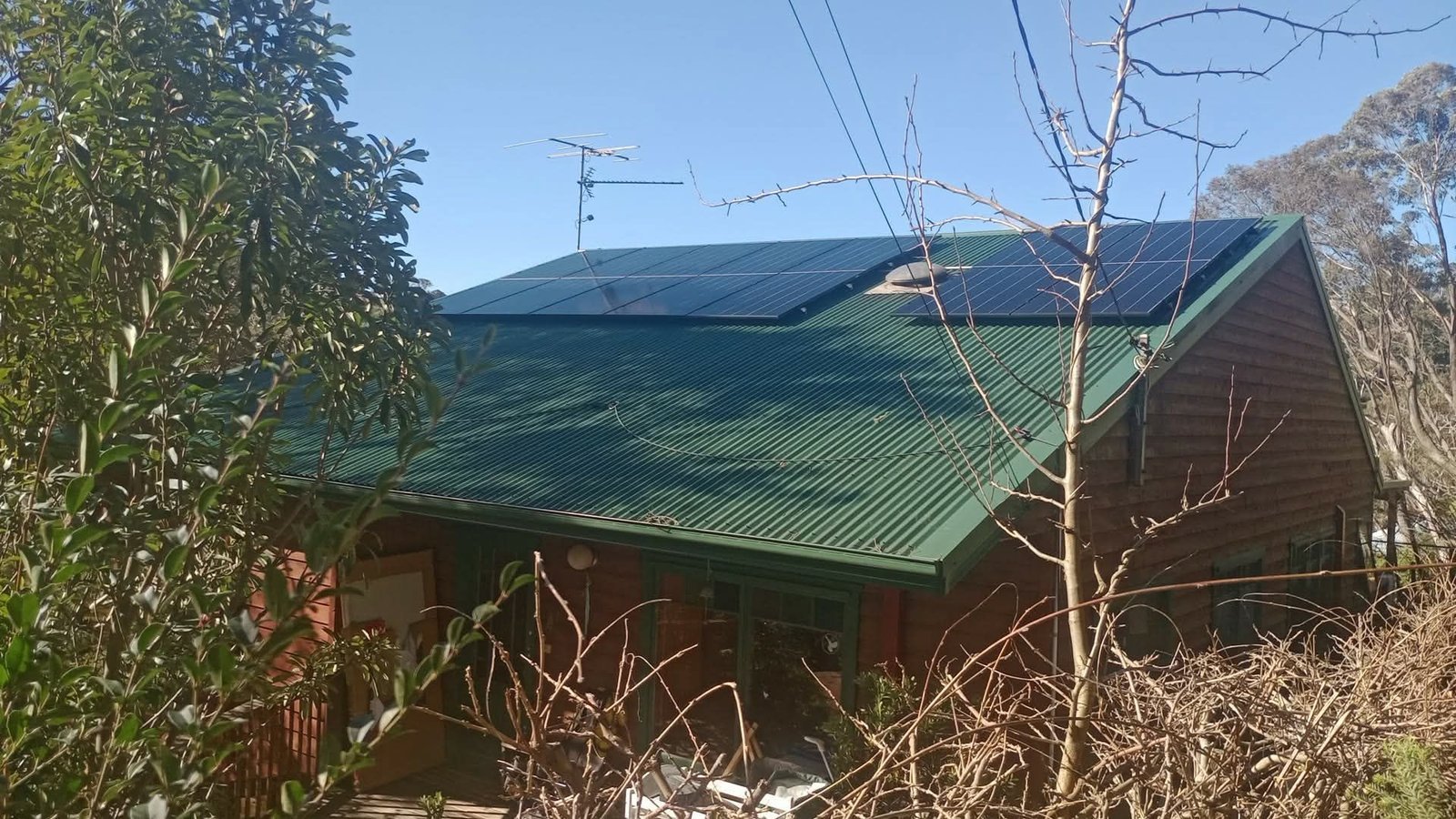 Rooftop solar panels installed on the green corrugated metal roof of Mike's timber home in Katoomba