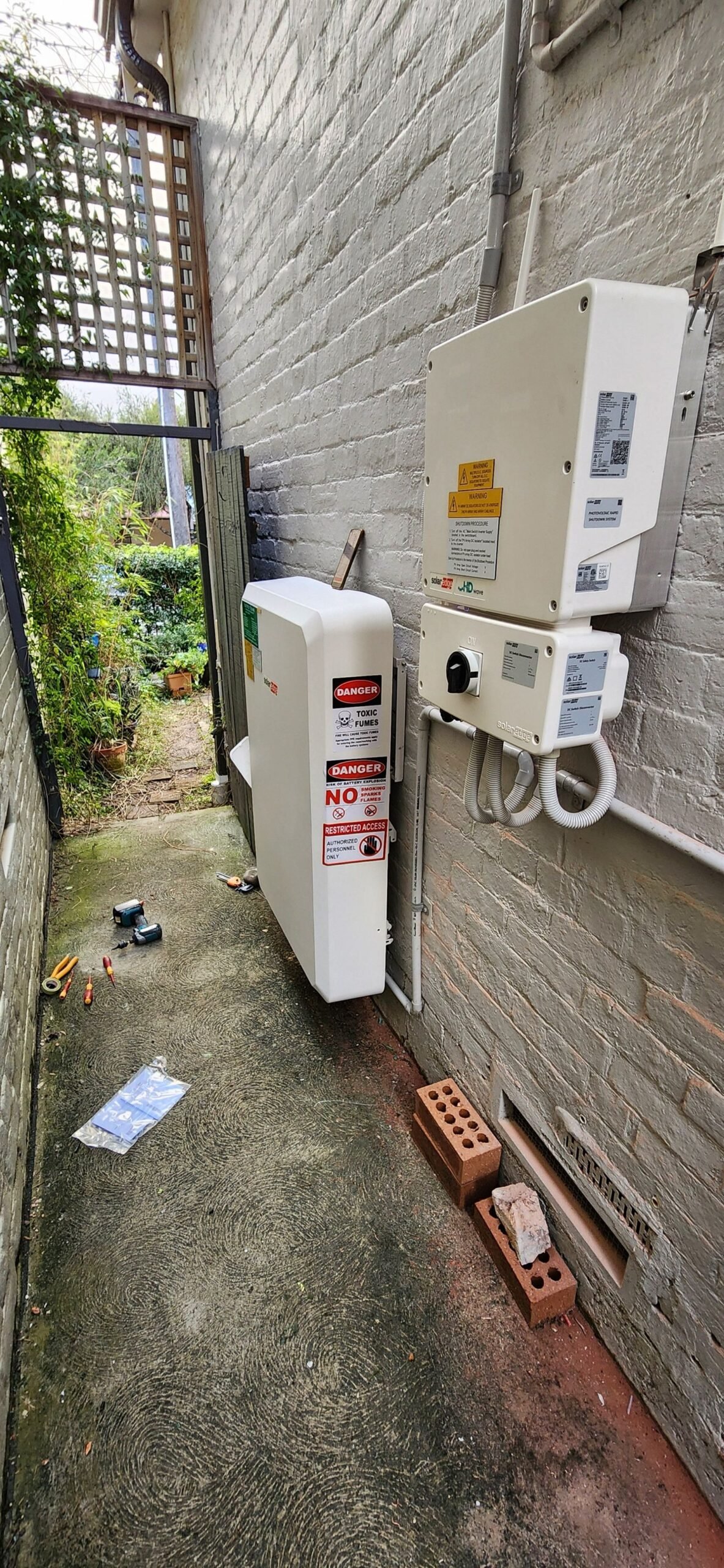 The installed SolarEdge smart inverter and battery storage unit mounted against the external brick wall