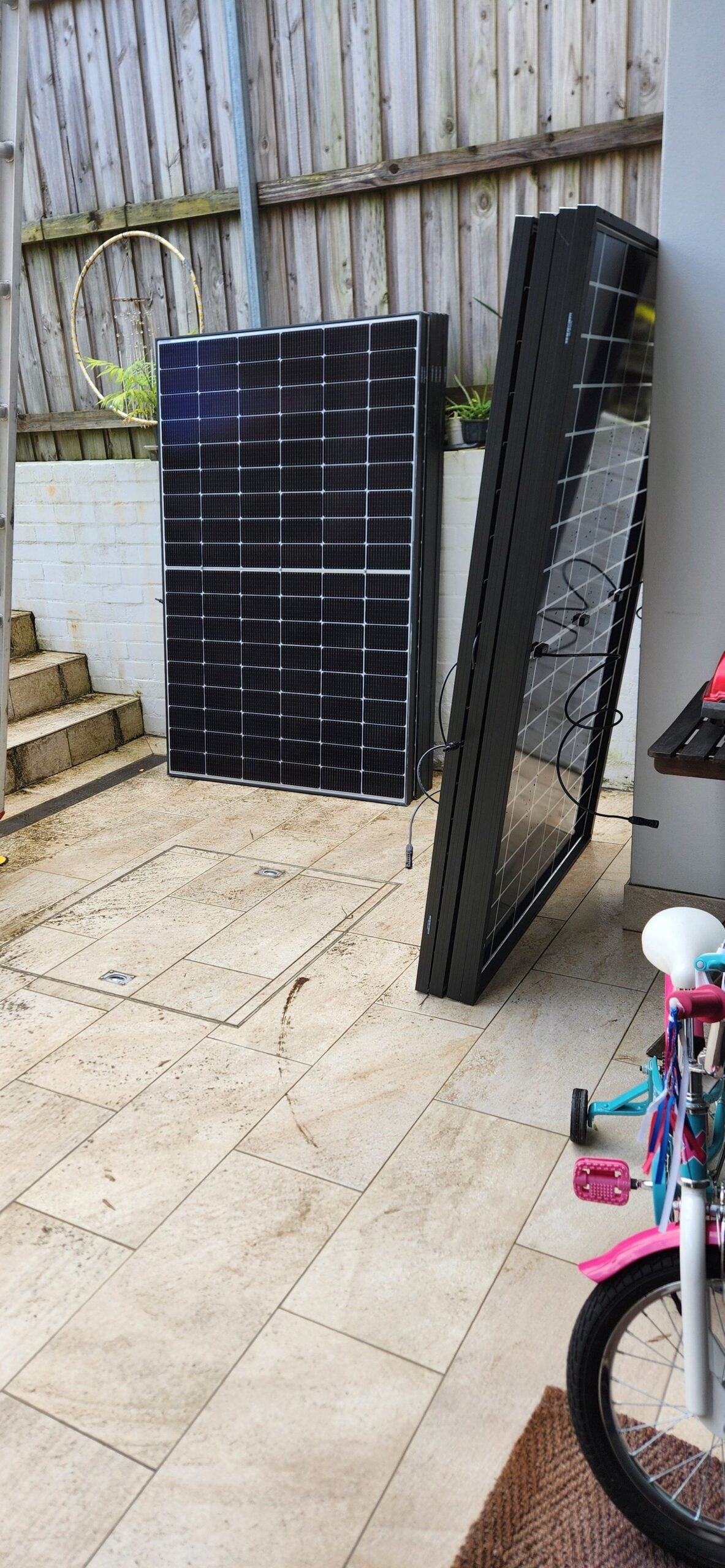 Rooftop solar panels leaning in the courtyard, ready for installation on Simon's townhouse roof